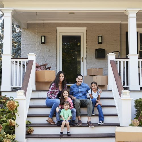 family-sitting-on-steps-of-new-home-on-moving-in-day
